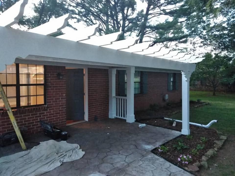 Covered porch entry with white posts and a brick home exterior